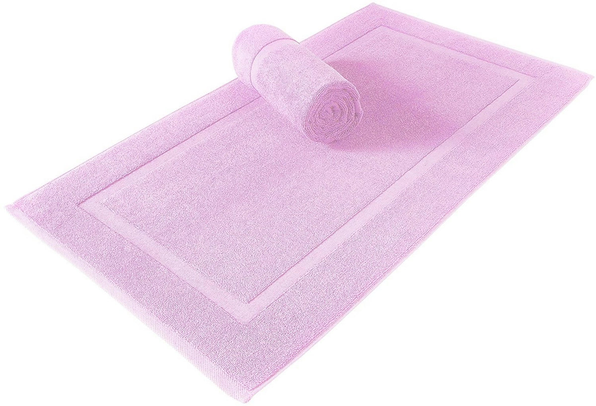 A light pink bath mat with a raised border and a matching rolled towel, shown on a plain white background.