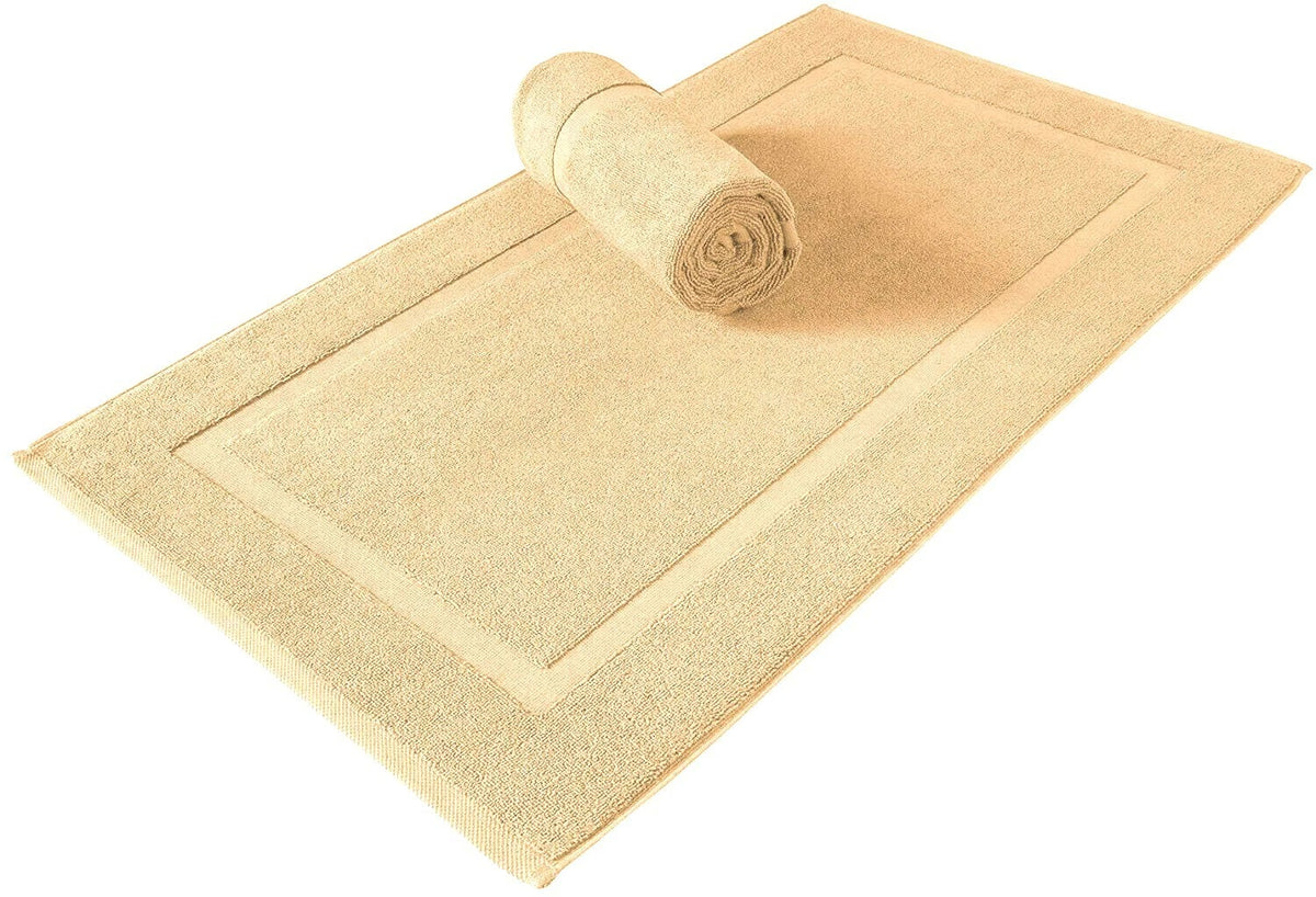 A beige bath mat with a raised border, shown partially unrolled with a matching rolled section placed on top, isolated on a white background.
